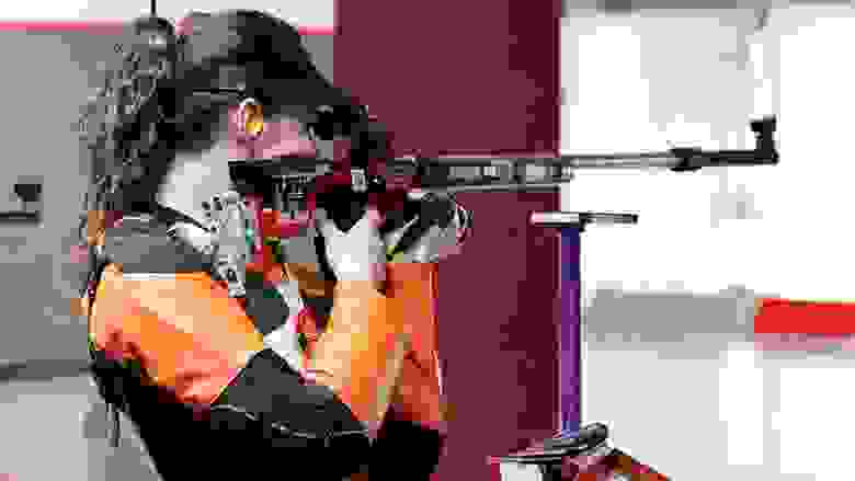Female Competitor Shooting a Rifle at an Indoor Range