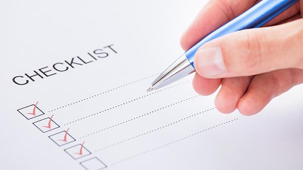 A hand with a pen ticking off boxes in a checklist