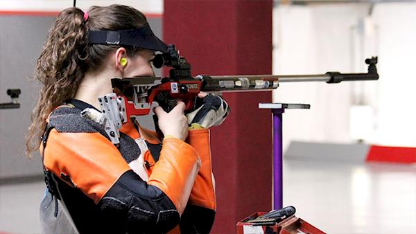 Female Competitor Shooting a Rifle at an Indoor Range