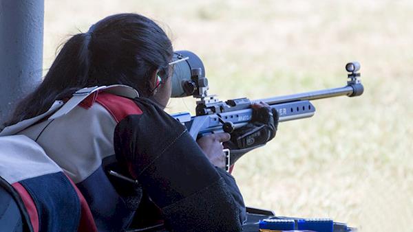 Female Competitor Shooting a Rifle at an Outdoor Range