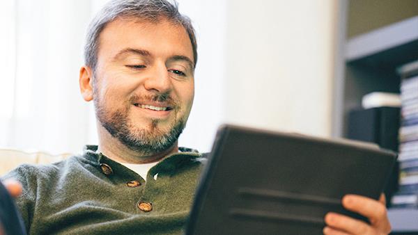 Bearded Man Smiling While Looking at his Tablet